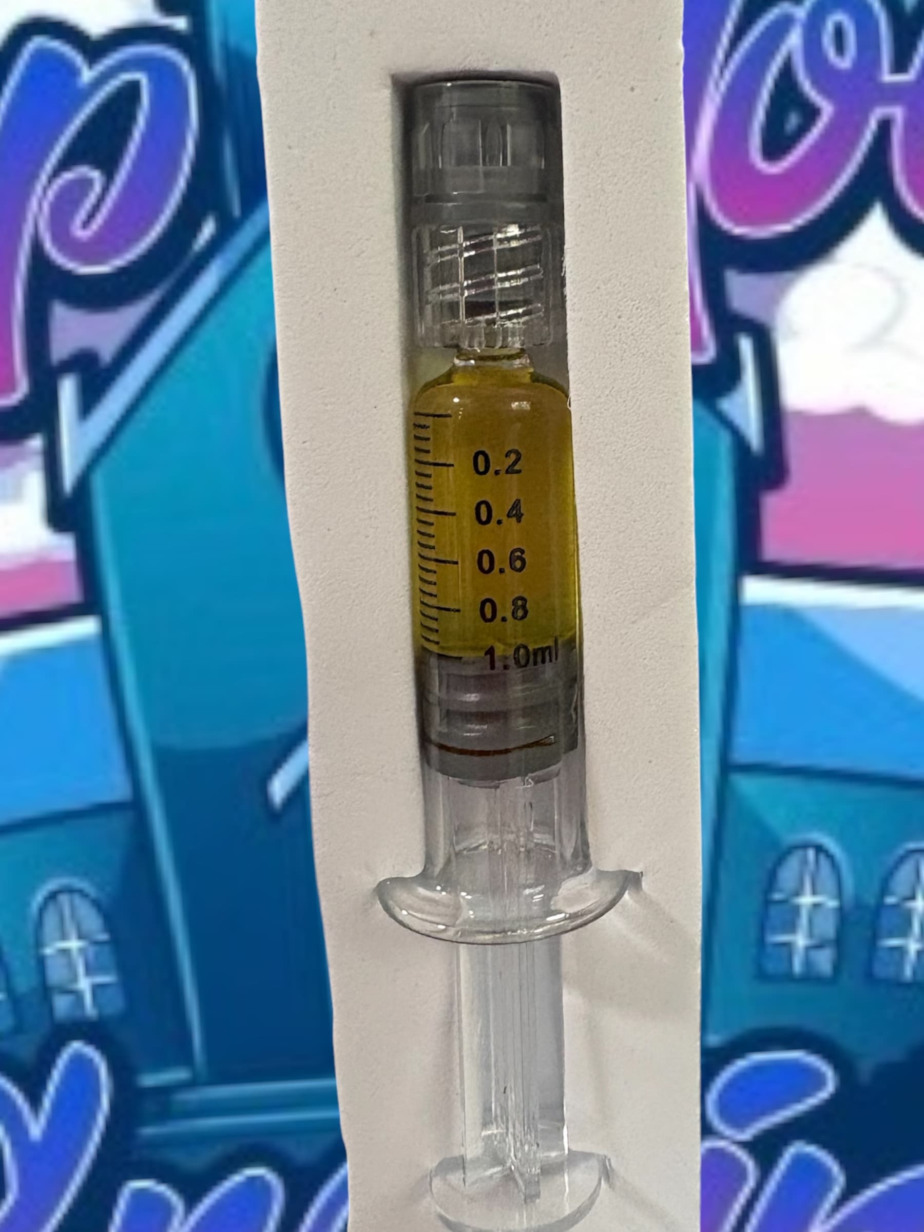 Clear syringe containing amber oil, marked with measurements, resting in a white foam insert.