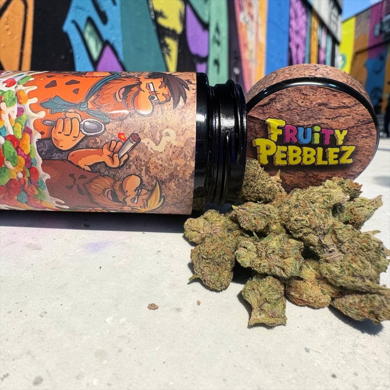 Cannabis buds spilled from a 'Fruity Pebblez' jar featuring cartoon characters and graffiti background.