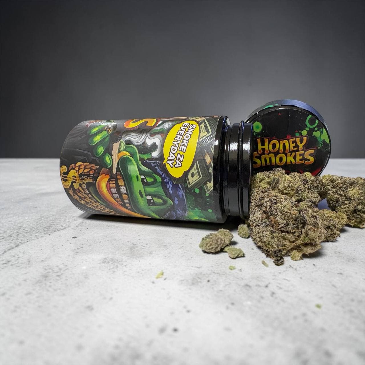 Dried cannabis buds spilling from a black Honey Smokes jar with a colorful alligator label.
