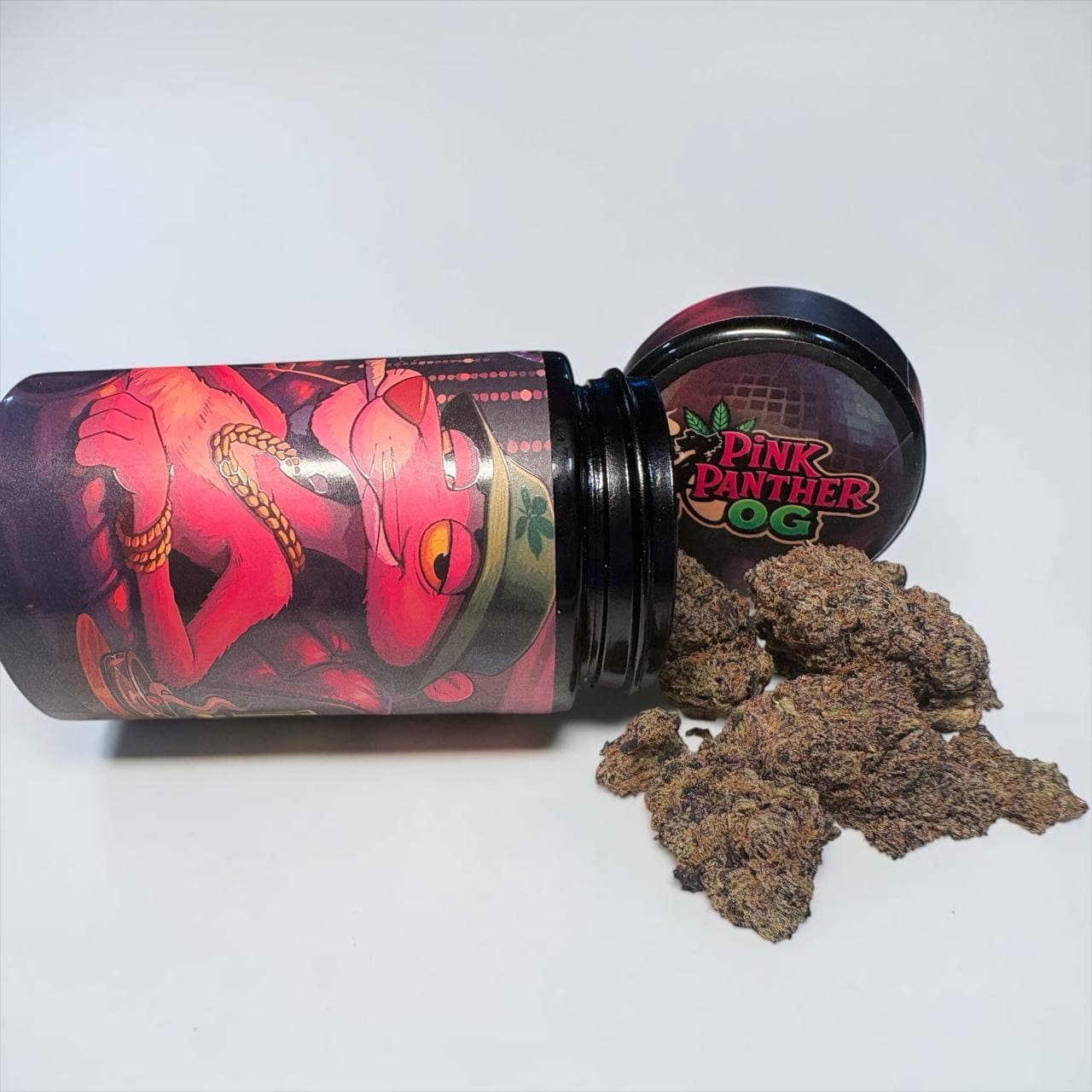 Dark purple cannabis buds spilled from a Pink Panther OG jar on white background.